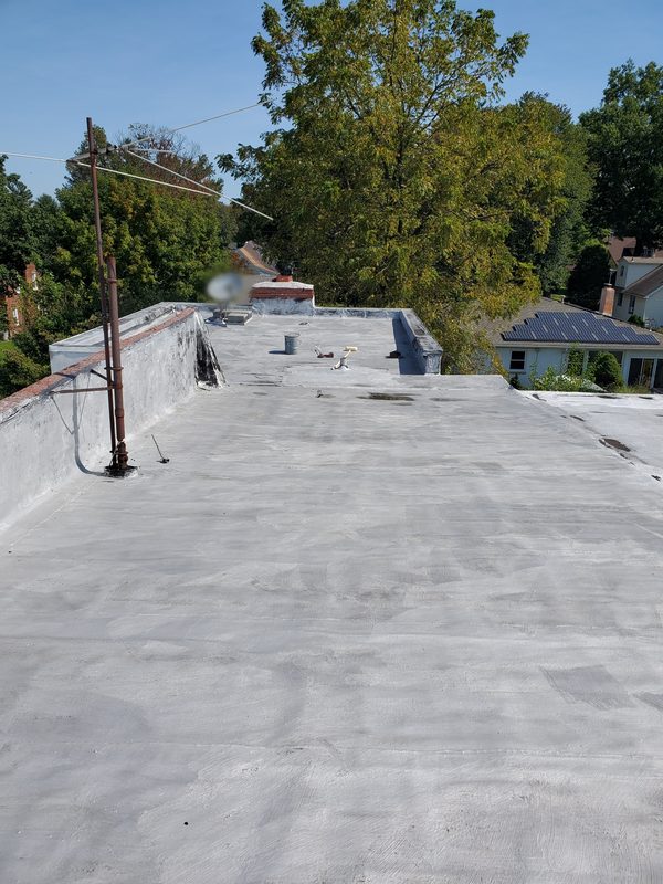 New light-gray reflective flat roof surface between parapet walls