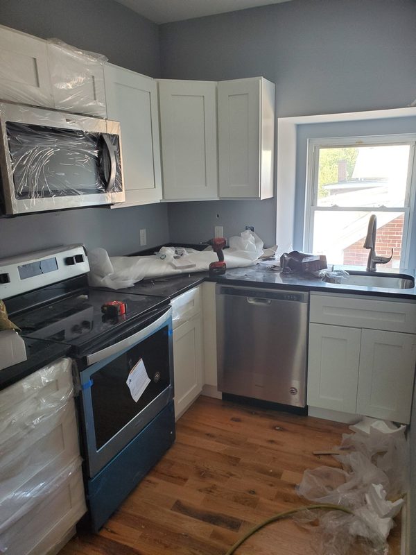 New kitchen with white cabinets, stainless steel range, microwave and dishwasher, and wood flooring