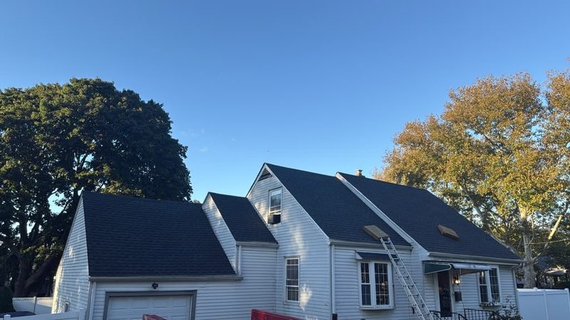 The same Cape Cod house after roof replacement: new dark architectural shingles on the main roof, dormer and garage